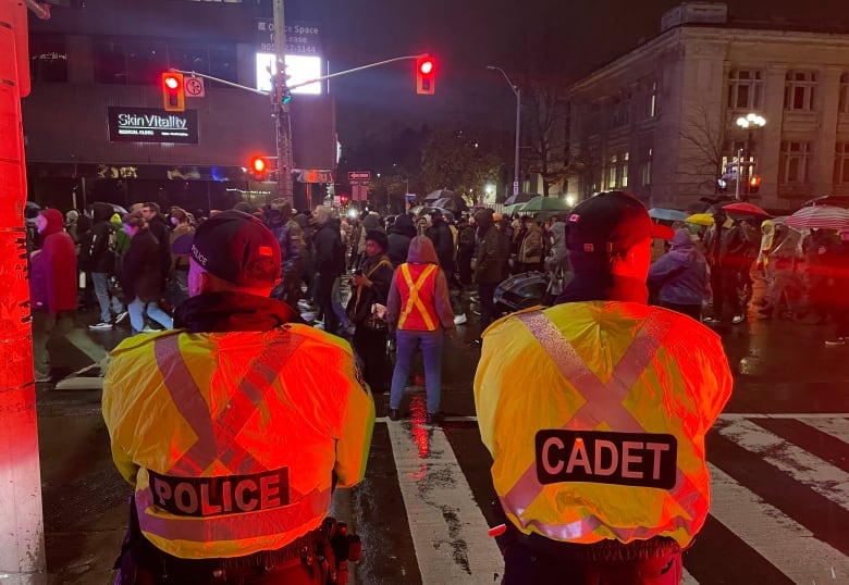 Two men look onto a crowd of people on the street.