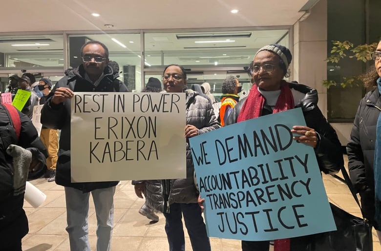 Three people holding two banners that read 