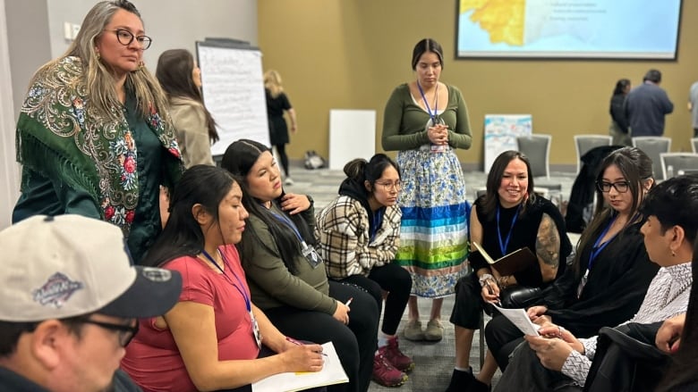 A group a youth, talking in a circle and taking notes. 