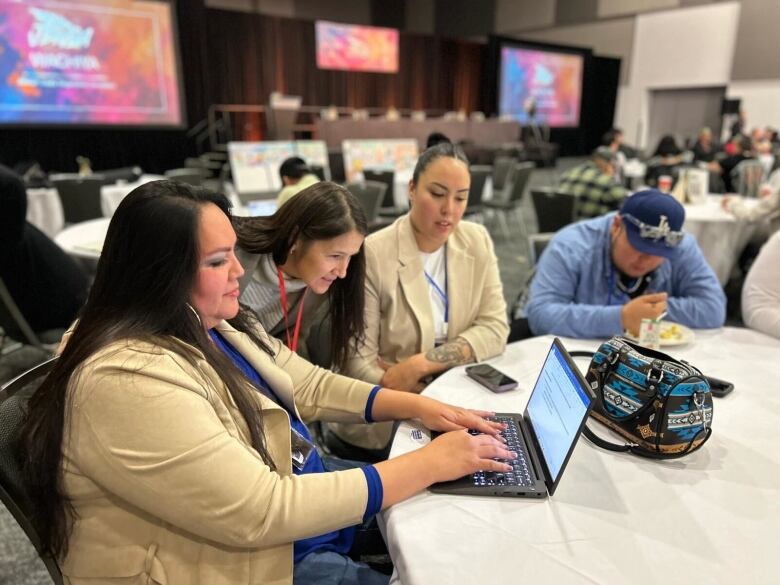 A group of people looking over a computer screen. 