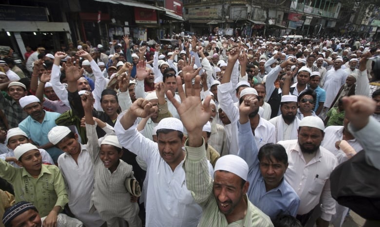 A large group of men raise their arms as they protest outside.