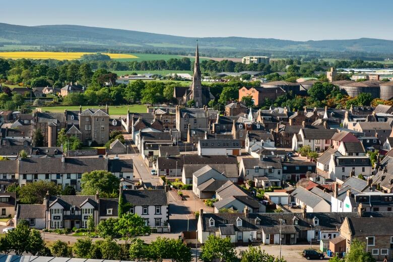 Ariel view of a picturesque town with green hills on the horizon and a church at the centre