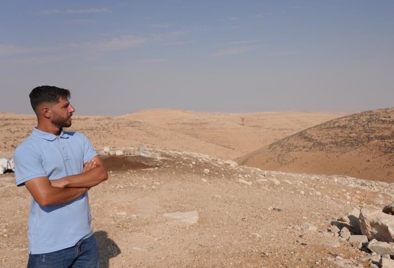 A man in a blue shirt looks out over a desert-like landscape. 