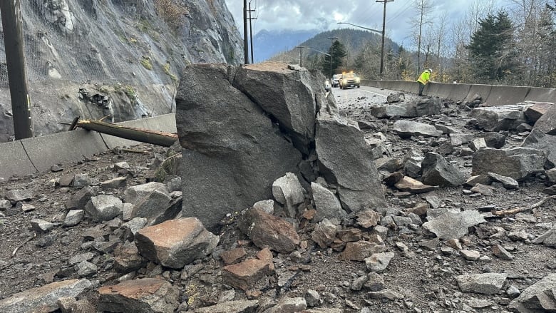 A huge rock and several smaller ones on a highway.