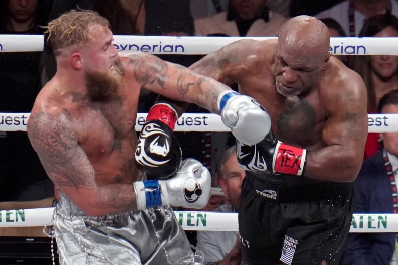 A man punches another man in a professional boxing ring.