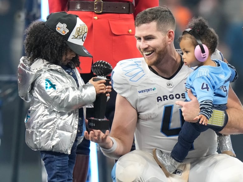 A football player and his daughters. 