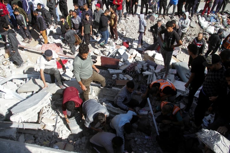 People stand atop rubble.