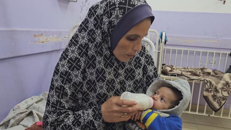 A woman is feeding her child milk.