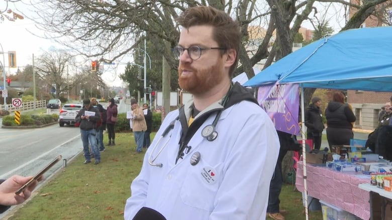 A doctor in a white lab coat outside.