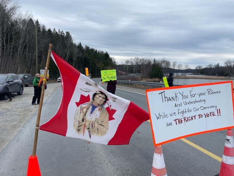 A sign with protestors and a flag.