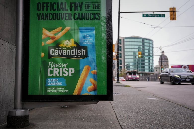 A green billboard advertising french fries is seen at a bus stop in a large city.