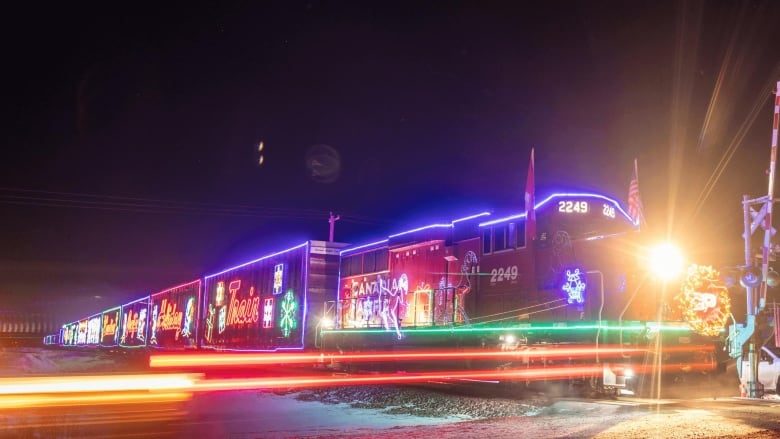 A large freight train lit up with Christmas lights.