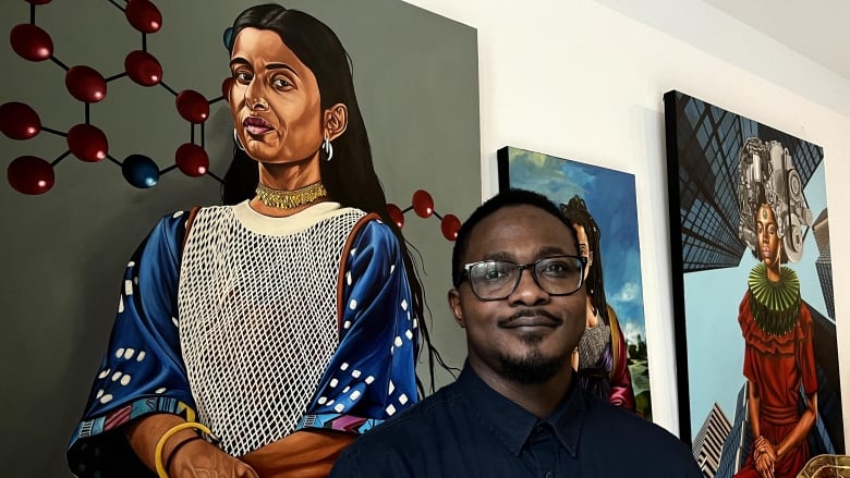 A Black man smiles in front of a painting of a South Asia woman. 