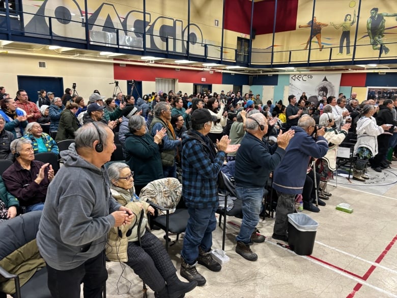 Some community members stand and clap after the apology