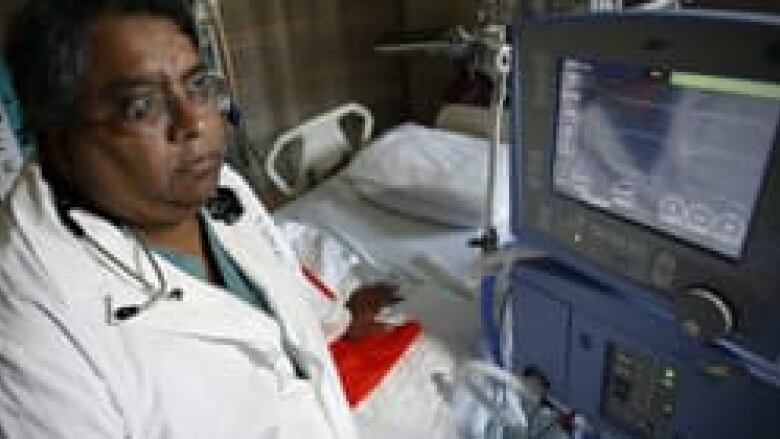 A man in a white lab coats stands at a medical device